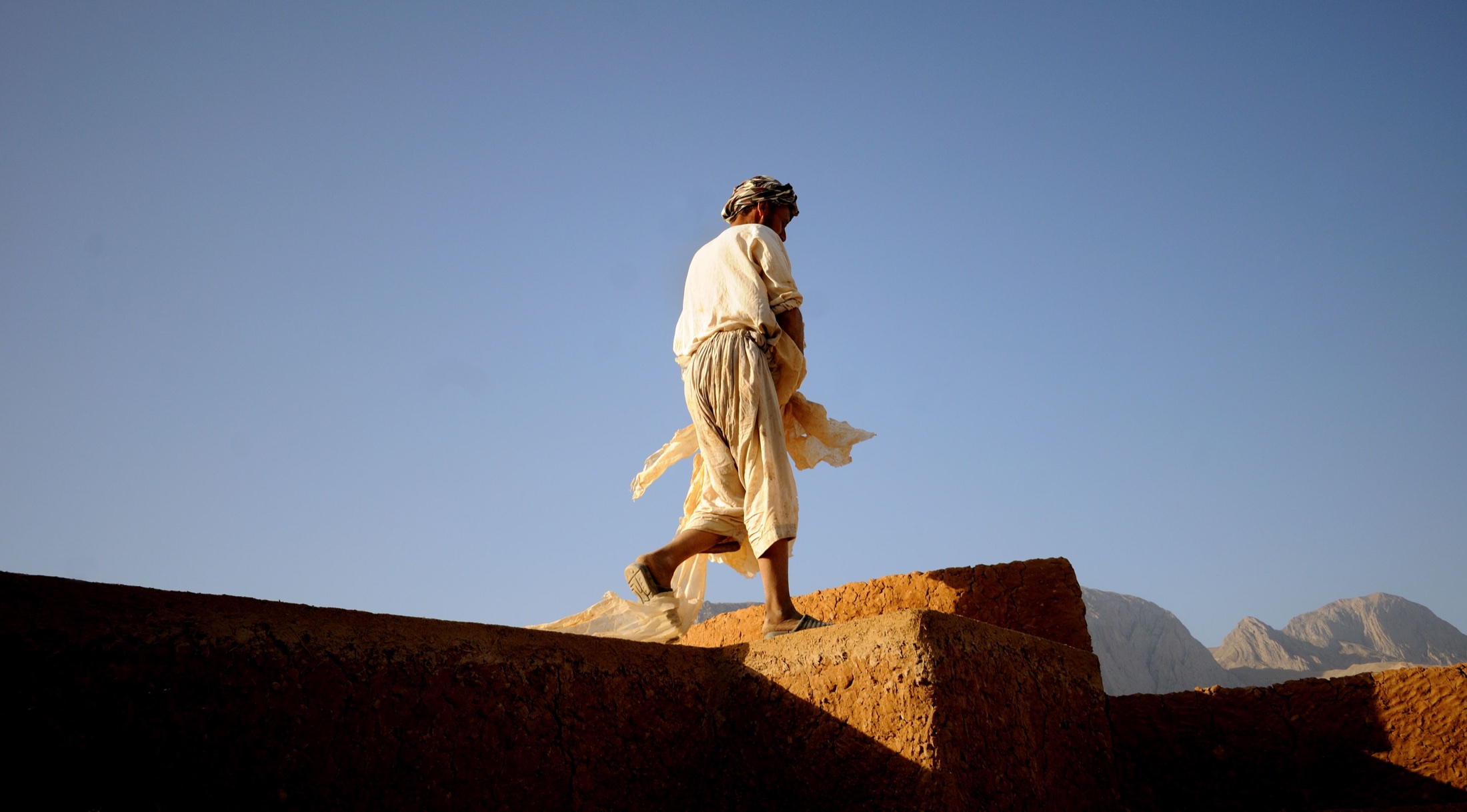 A local heritage worker crossing a historic earthen structure in Kholm, Afghanistan